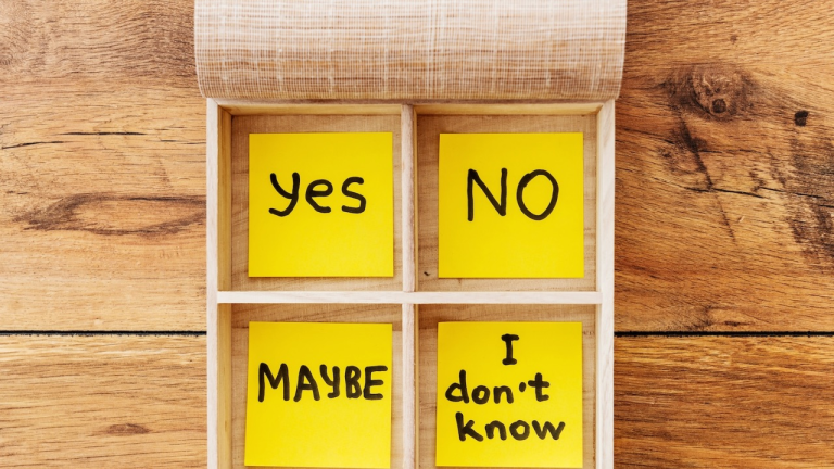 Four sticky notes in a wooden box labeled ‘Yes,’ ‘No,’ ‘Maybe,’ and ‘I don’t know.’
